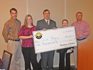 People from Our Place holding giant check.